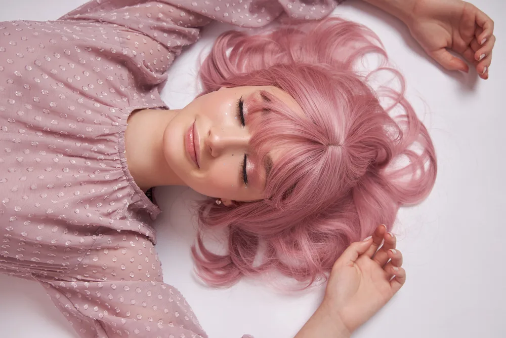 Dusty Rose Gold hair on a woman in a pink shirt lying down