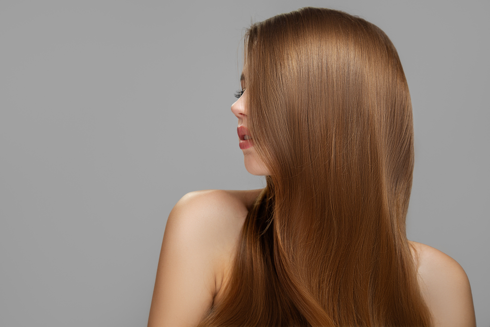Light Golden Brown, one of the best hair colors for pale skin, on a woman in a grey room