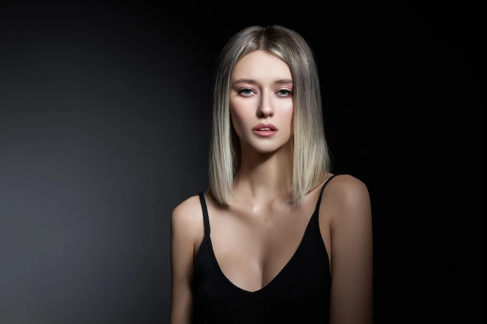 One of the best hair colors for pale skin, Ash Brown to Blonde Balayage, on e woman in a black shirt