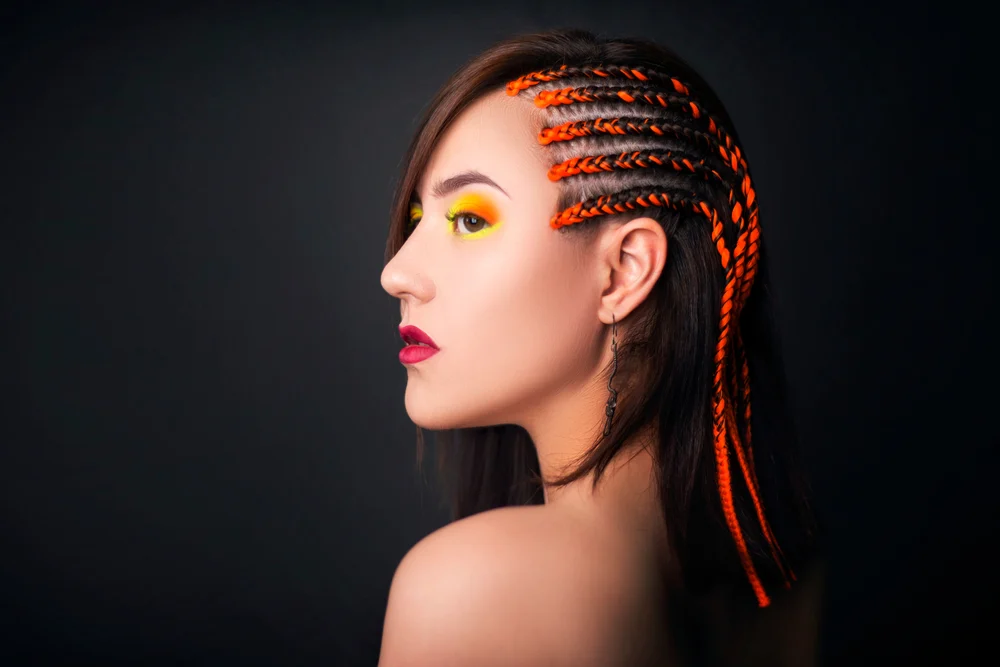Thai braids with cornrows on the side on an Asian woman with yellow makeup around her eyes and red lips