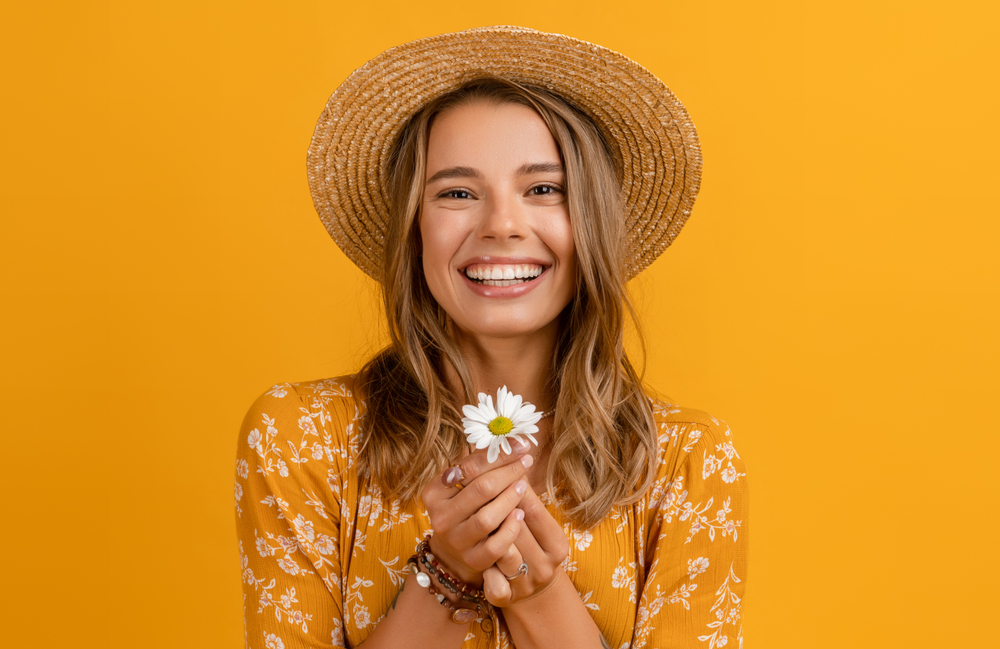 Golden Bronde summer hair color on a woman in a hat in an orange room