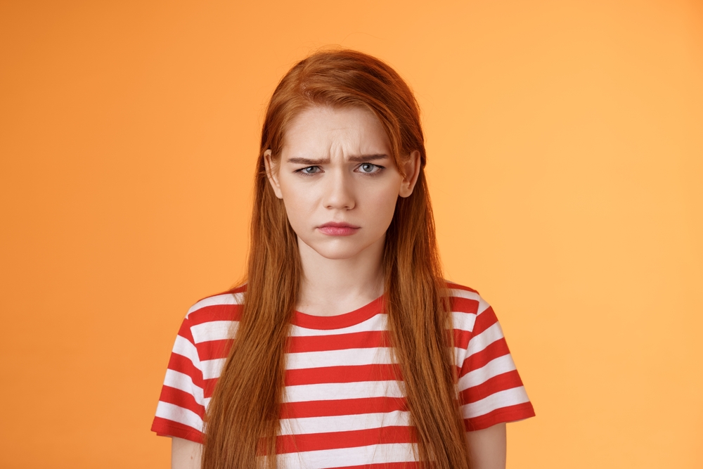 Redhead in an orange room looking offended because someone called her a ginger