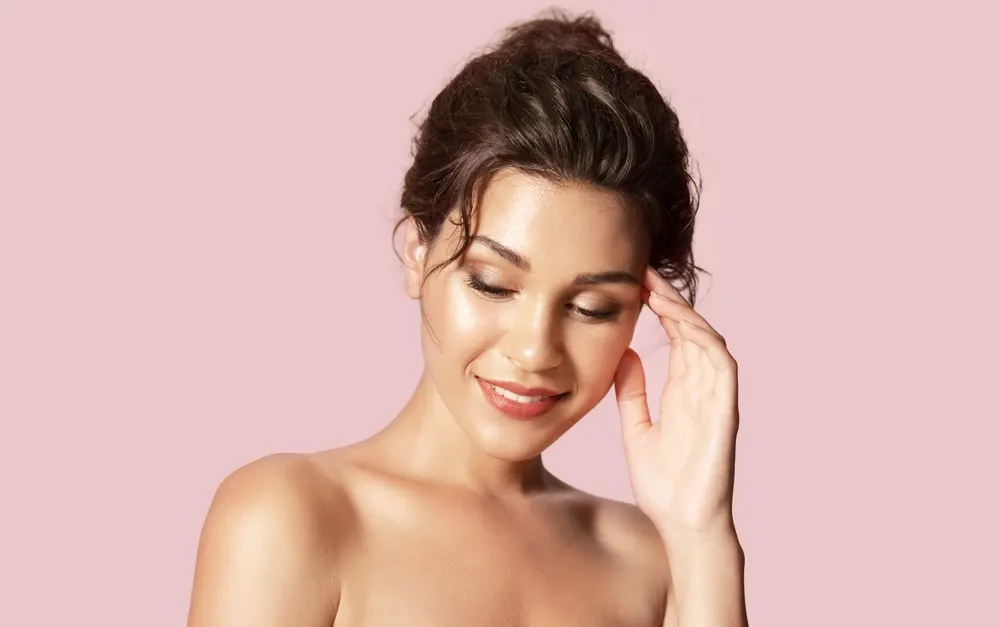 Image of a woman holding her hand to her forehead for a piece on the best hair color for olive skin