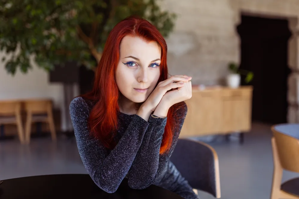Woman with red hair looks at the camera for a piece on the best hair color for neutral skin tones