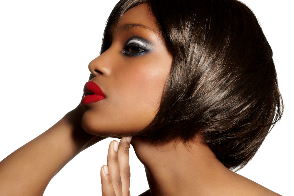 Woman with a short bob haircut in a white room holds her ear for a piece on the best hairstyles for black women over 50