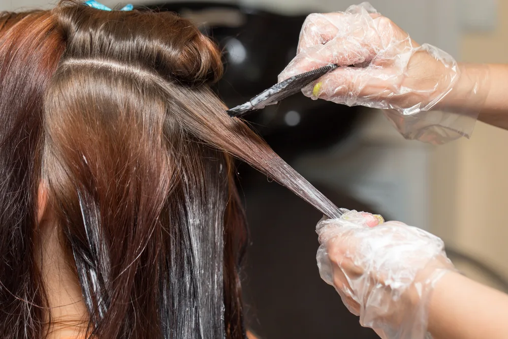 Woman pulling a brush through brown hair for a piece on the best hair color for gray hair ideas