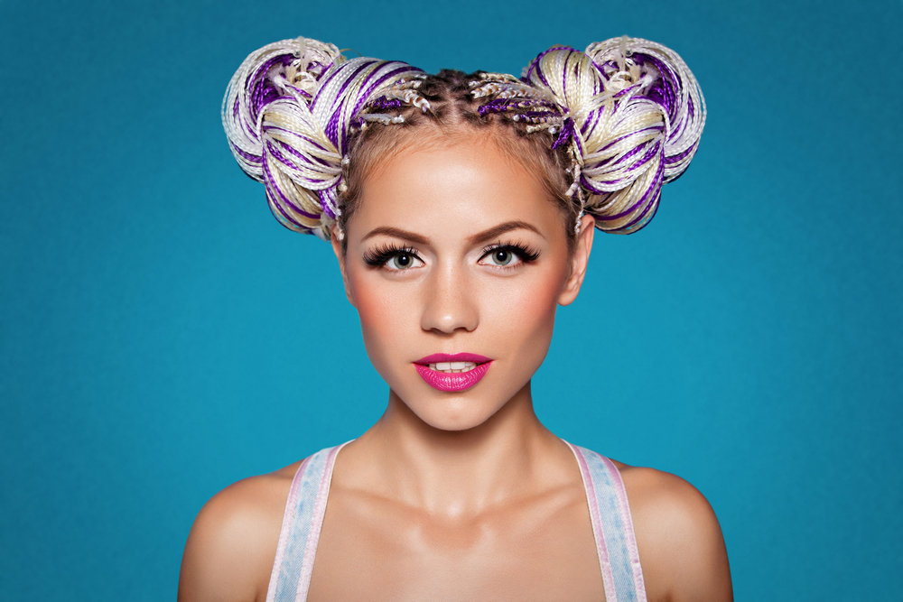Colorful Space Buns made from Thai Braids on a woman with olive skin in a blue room