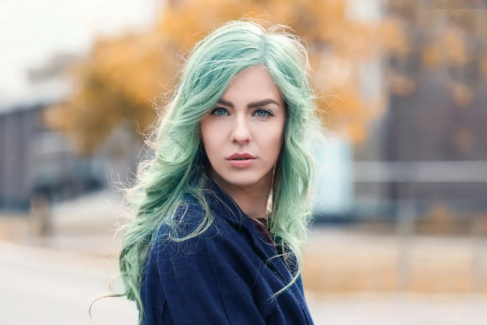 Woman with blue eyes an green hair pictured looking at the camera