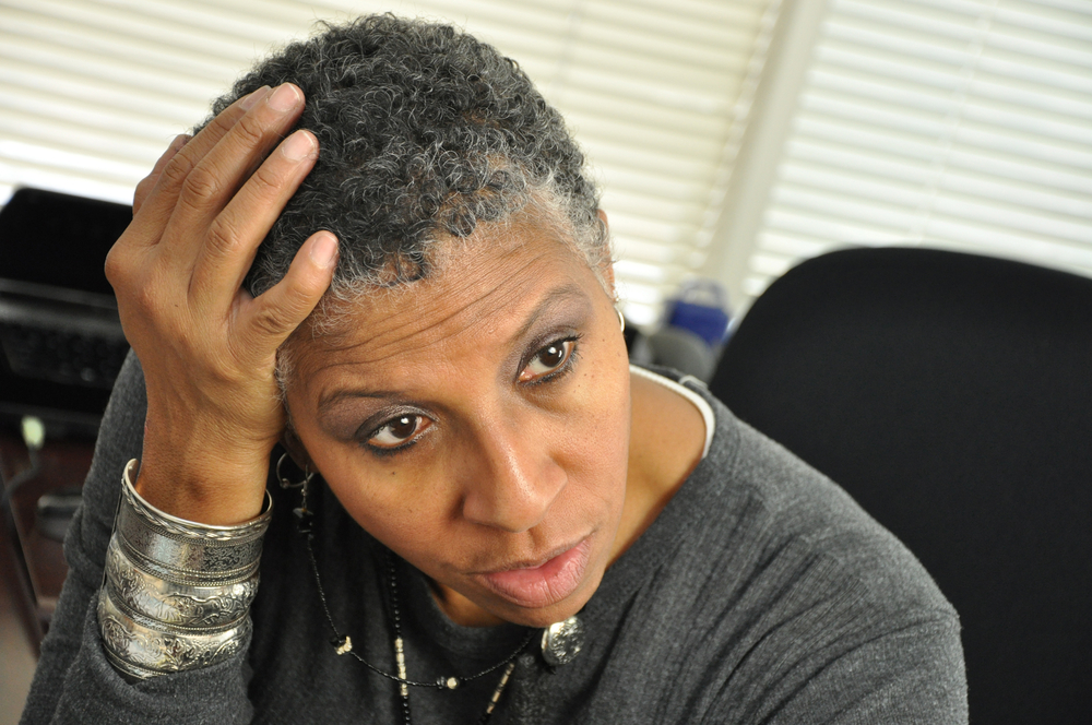 Woman holding her head for piece on the best hairstyles for black women over 50