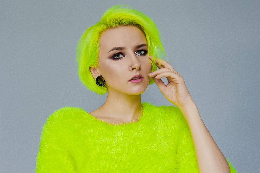 Neon Peridot Yellow-Green, one of the best unnatural hair colors for blue eyes, pictured on a woman in a bright lime green shirt