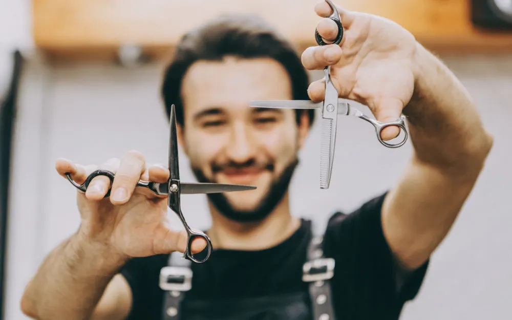 For a piece on how to sharpen hair clipper blades, a man holding two pairs of clippers in a square pattern