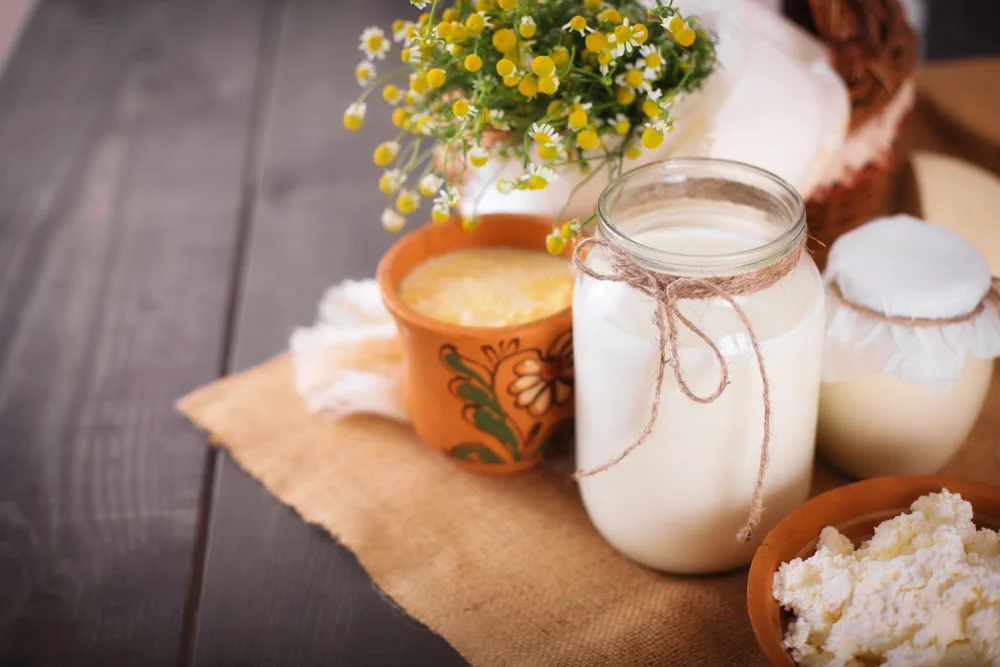 For a FAQ section on goat milk benefits for hair, a jar of milk next to flowers on a table
