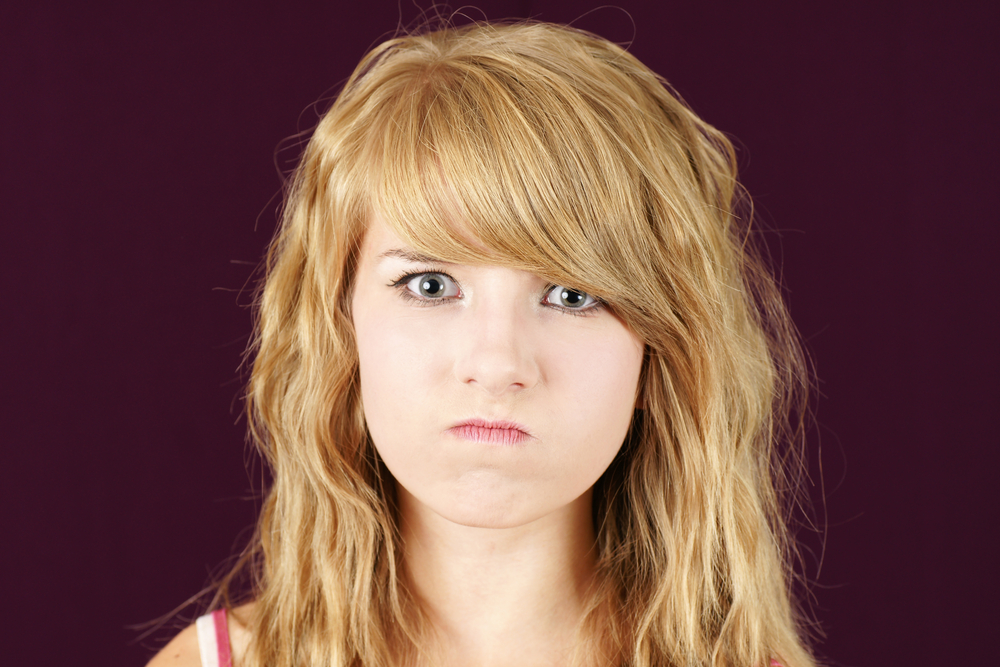Woman snarling and wondering what does brassy hair look like in a black room
