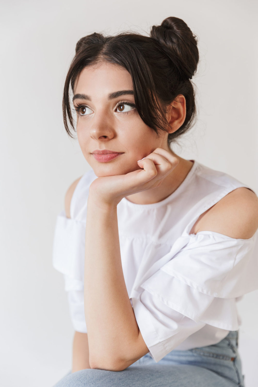 Quick Space Buns pictured on a woman in a white shirt for a piece on quick hairstyles for women