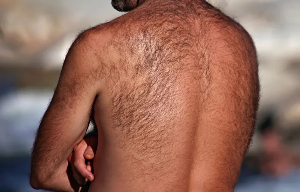 Man with lots of hair on his back crosses his arms