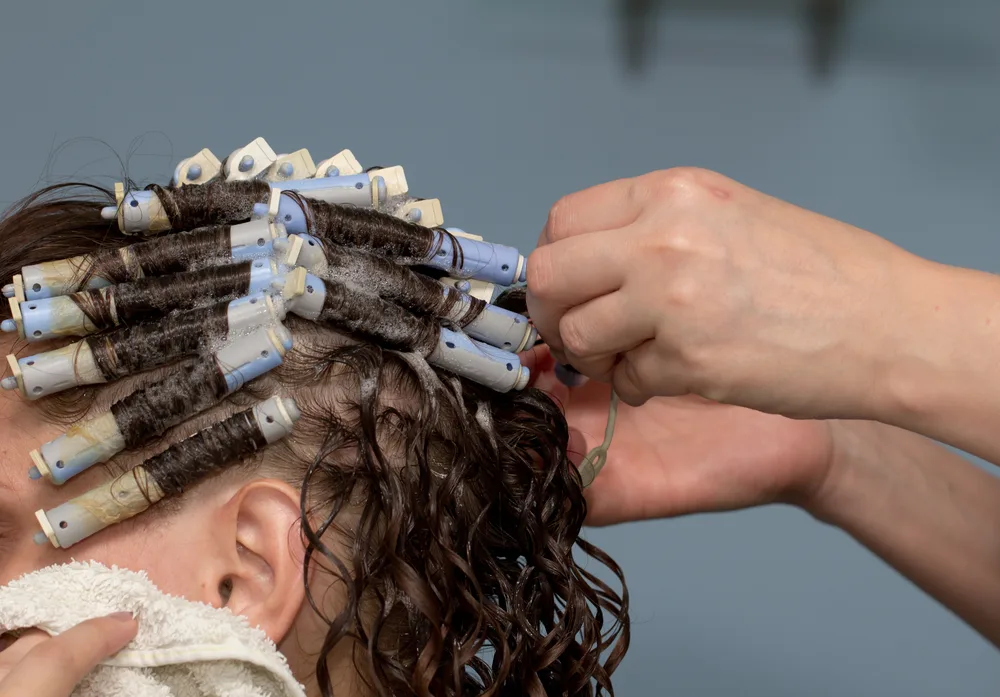 Image of a woman getting a perm for a guide to bleaching permed hair