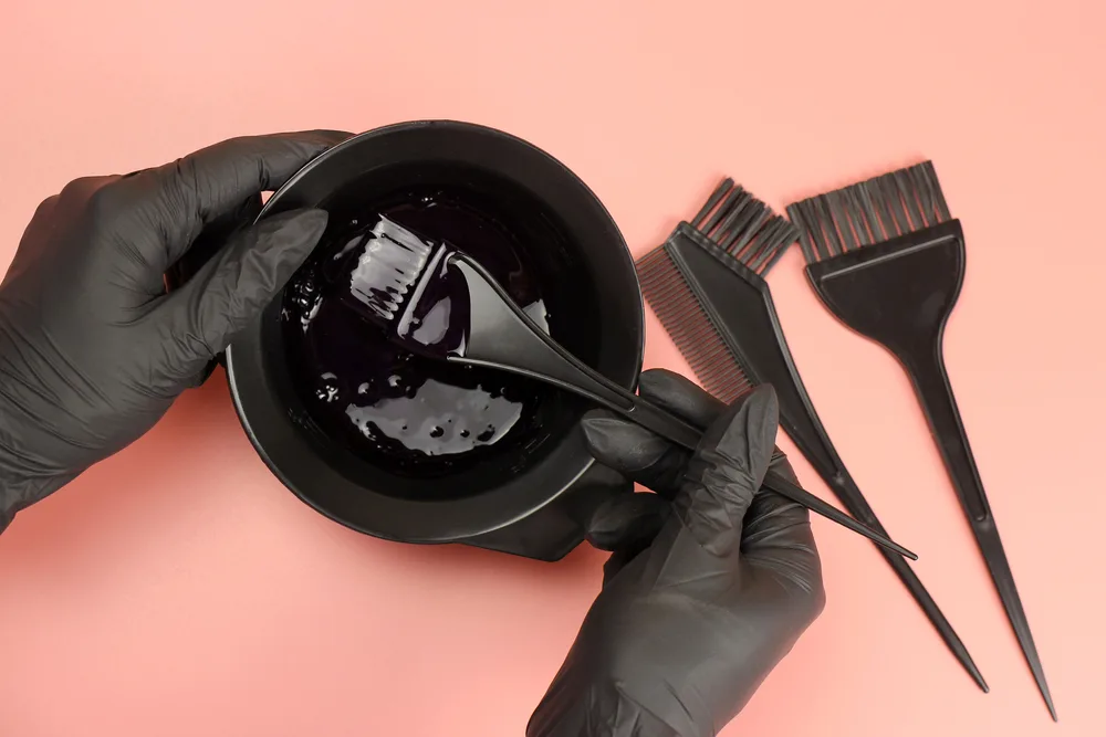 Image of a bowl of black hair dye on a salmon table for a piece on what hair color fades the slowest