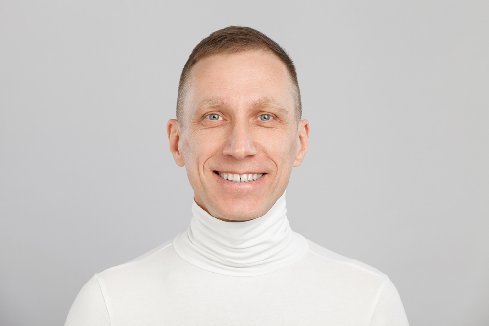 Man with a buzz cut fade in a white turtleneck