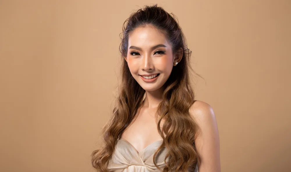 Cute thin light brown haired Asian woman in a silver dress smiling