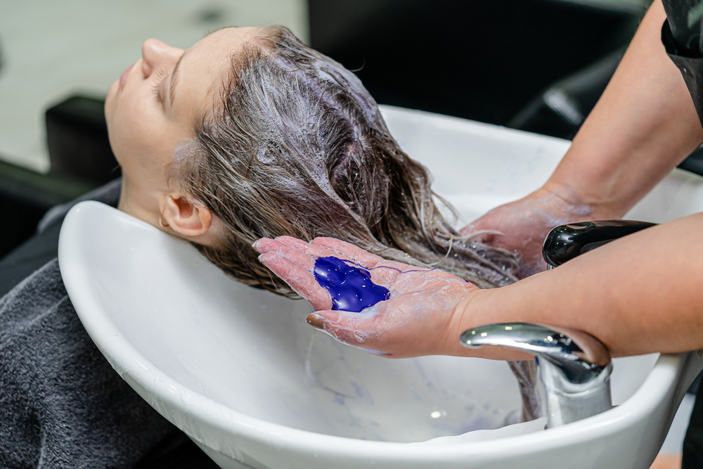 Woman using a purple shampoo wondering what does purple hair look like when it fades