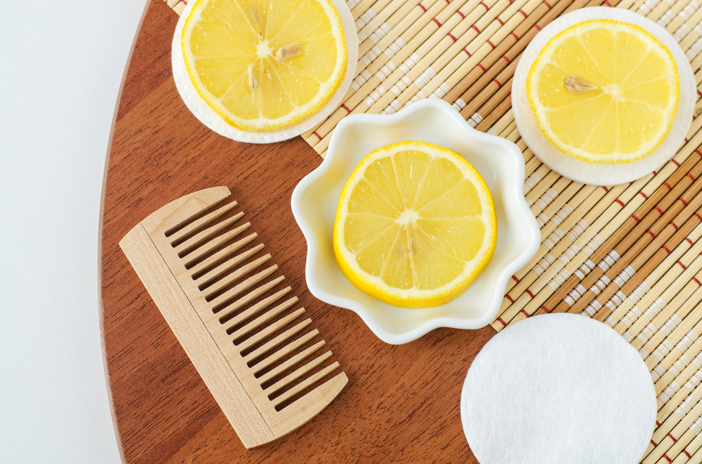 Several slices of lemons next to a wooden comb on a table for a piece on is sun in hair lightener good for your hair
