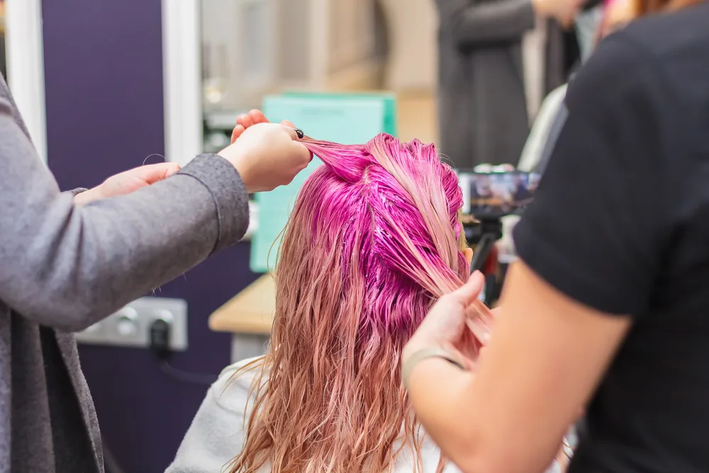 Woman getting her blonde hair dyed pink in a salon