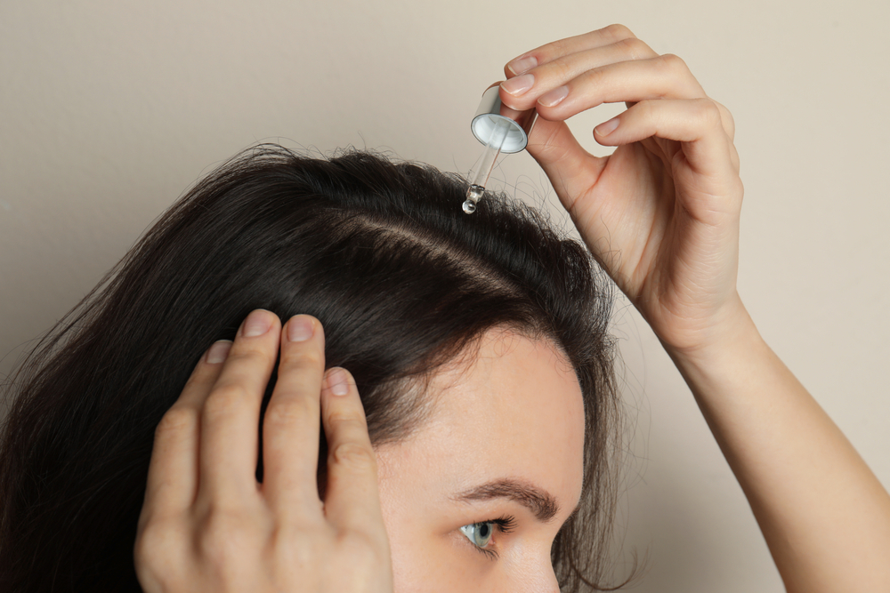 For a piece on can your hair get moldy, a woman treating her scalp with essential oils