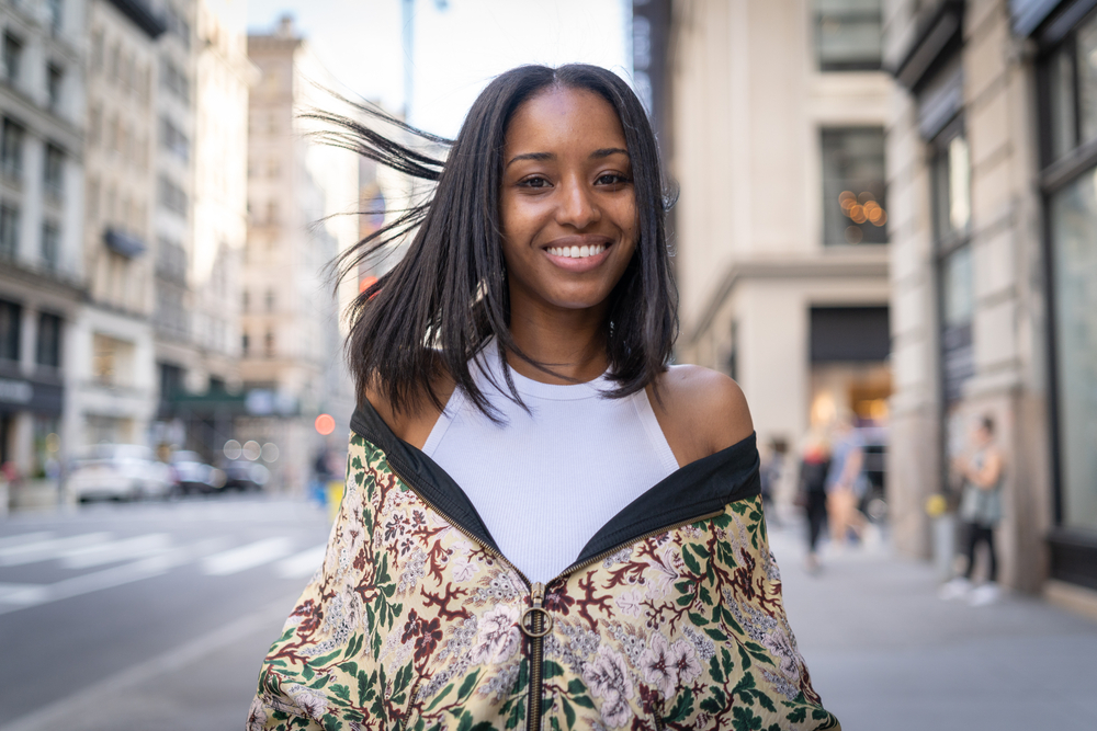 Người phụ nữ trẻ da đen được điều trị bằng axit amin có mái tóc siêu thẳng khi đứng trên đường phố ở một thành phố lớn