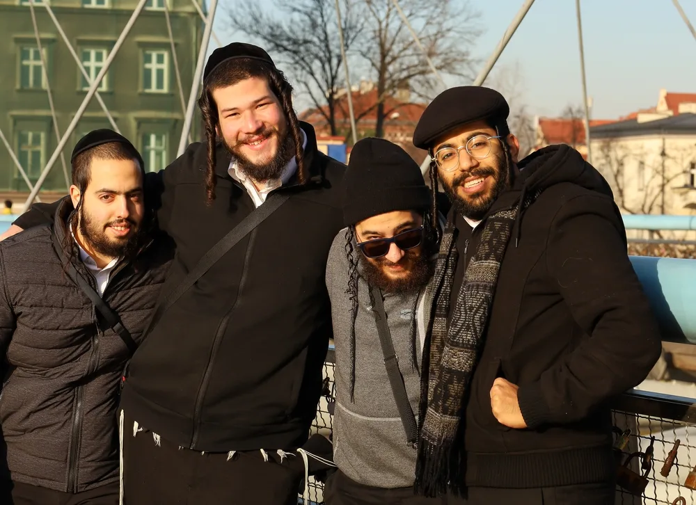 Four man in Poland smiling and embracing for a piece on why do jewish people have curly hair