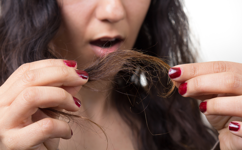 Woman looking at her hair in disbelief that she has split ends