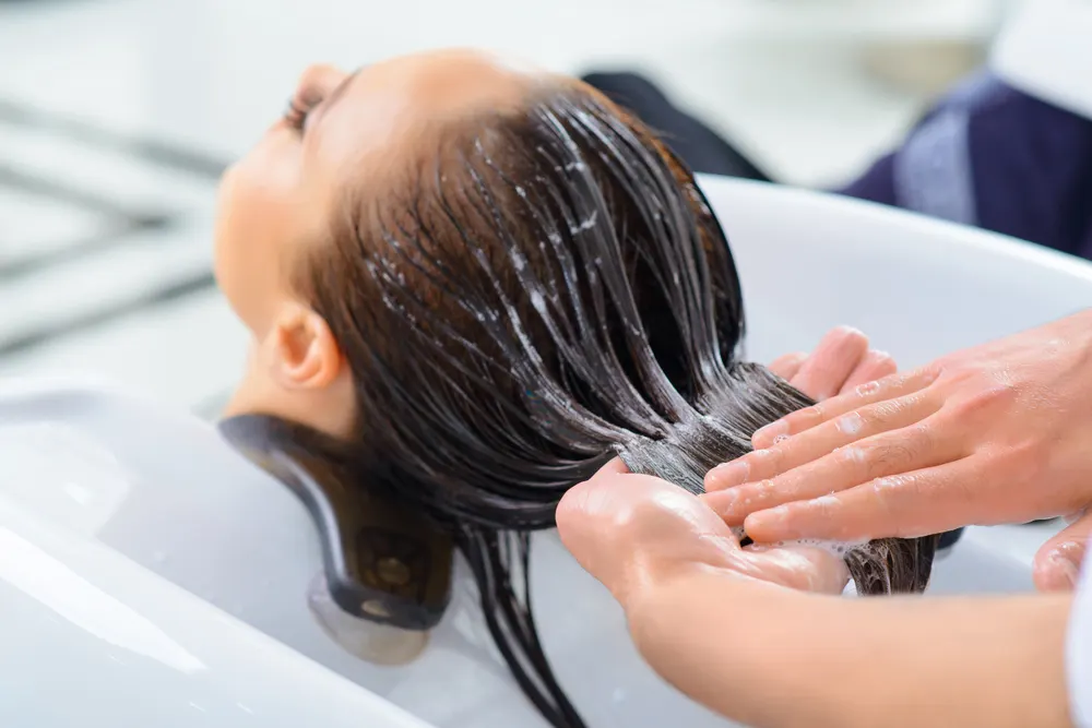 Image of a woman clarifying her hair to remove toner in a salon
