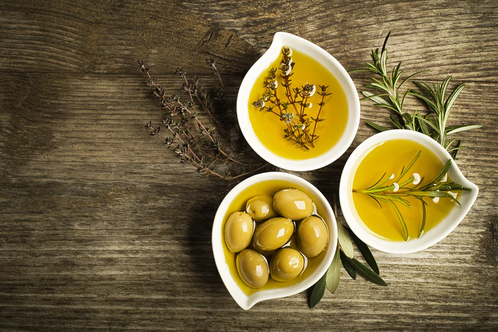 Several containers of olive oil pictured in jars on a wooden table