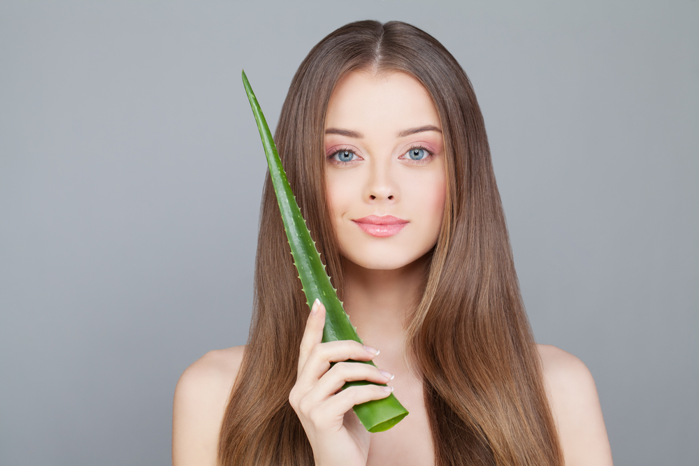 Woman holding an aloe plant up to her face wondering how often can i use aloe vera gel on my hair