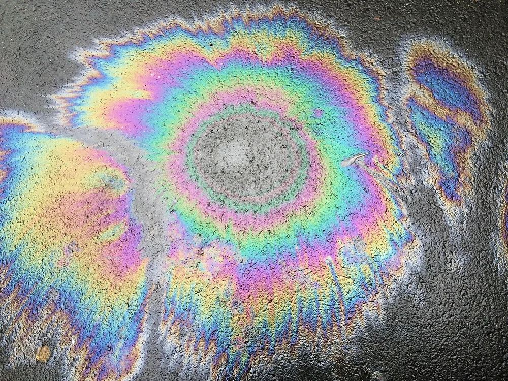 Oil spilled on concrete for a piece on what oil slick hair looks like