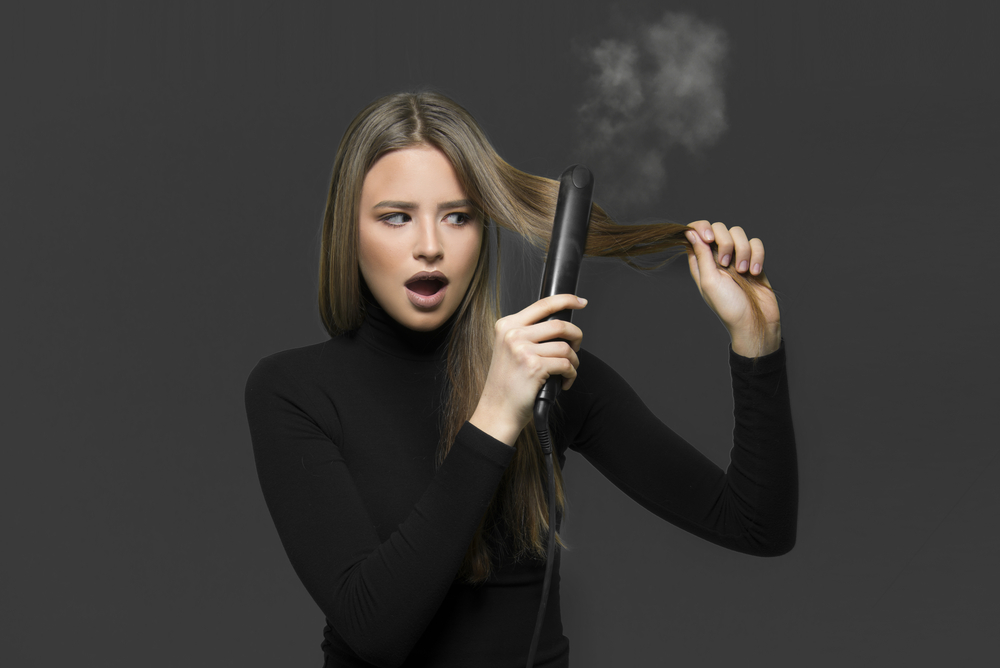 Woman making her hair smell like smoke by leaving a hot tool on it for too long