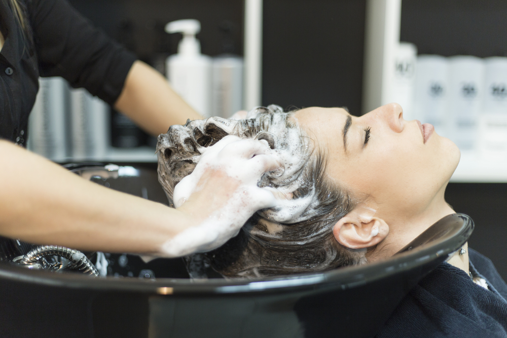 Woman in a salon chair wondering what does clarifying shampoo do to colored hair