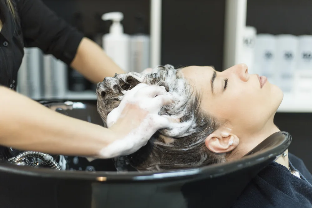 Woman in a salon chair wondering what does clarifying shampoo do to colored hair