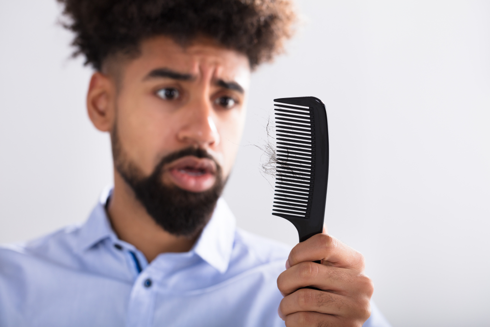 Man holding a black comb and looking in horror as his hair broke and wondering how to stop natural hair from breaking