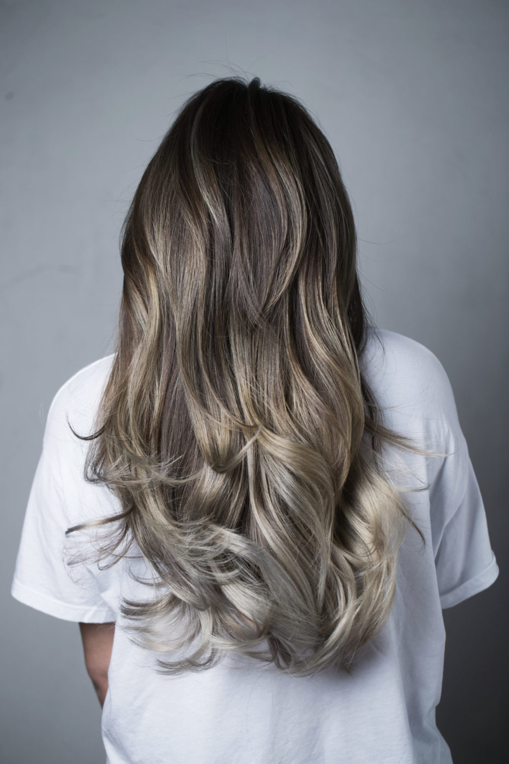 As a featured brown to blonde ombre color idea, a woman wears Espresso Brown to Ash Blonde Ombre Melt