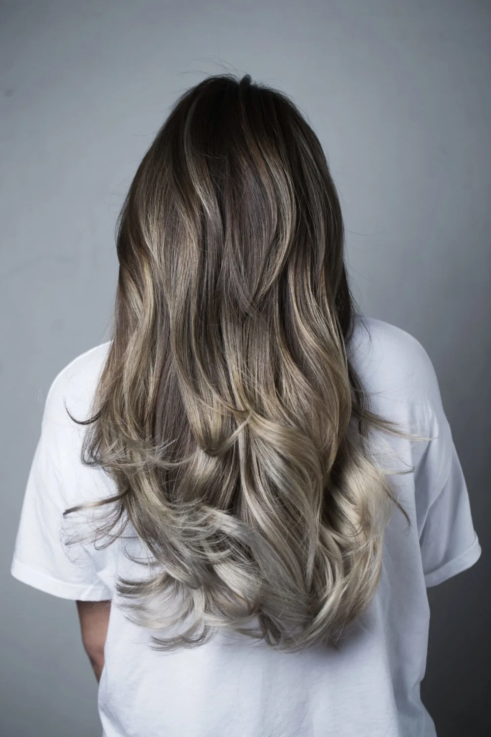 As a featured brown to blonde ombre color idea, a woman wears Espresso Brown to Ash Blonde Ombre Melt