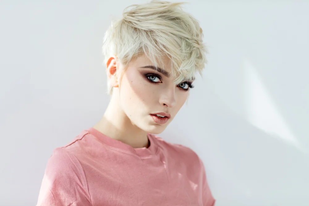 Woman with short layered hair in a pink shirt with blonde locks