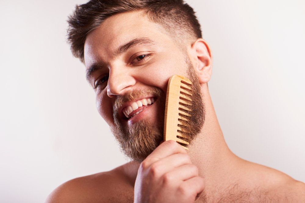 Man combing beard oil through his hair for a piece on does beard oil help beard growth