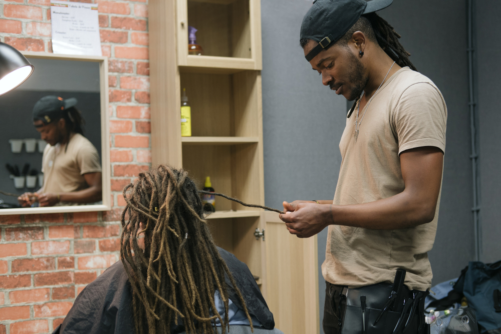 Người đàn ông tết tóc cho một người đàn ông trong một tiệm làm tóc ở Châu Phi để được hướng dẫn về các vị trí kích thước tốt nhất cho mái tóc đẹp