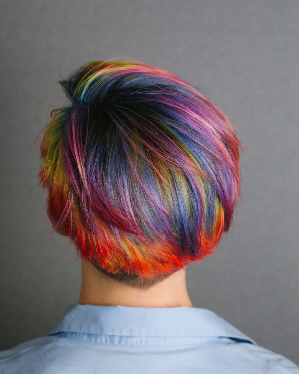 Bright rainbow hair on a woman in a blue shirt