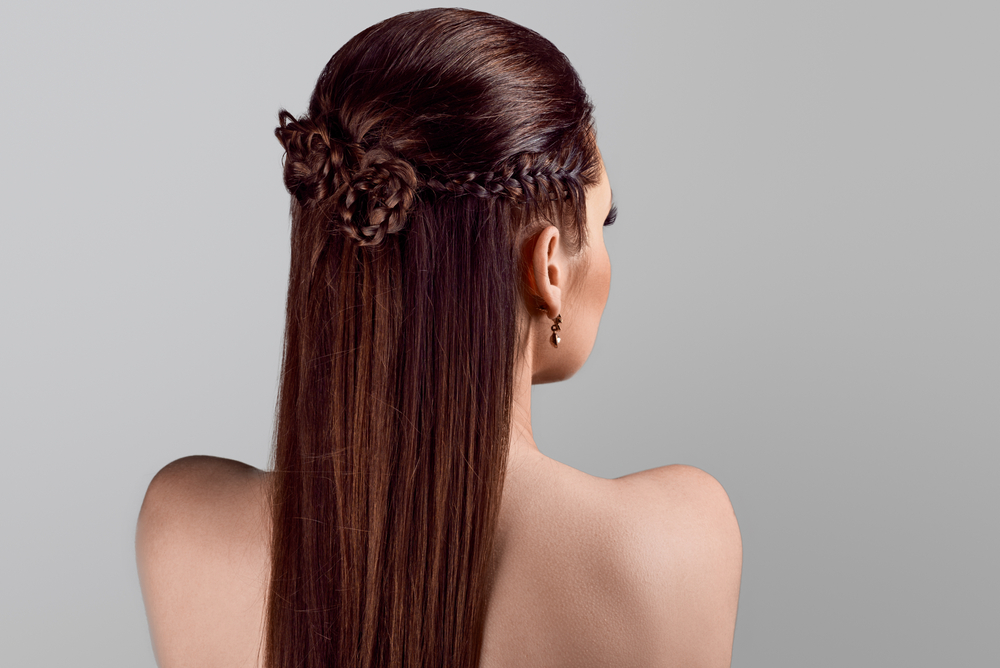 As a featured style for a roundup of gorgeous prom hairstyles, a woman wears a Sleek Spiral Braided Half-Updo