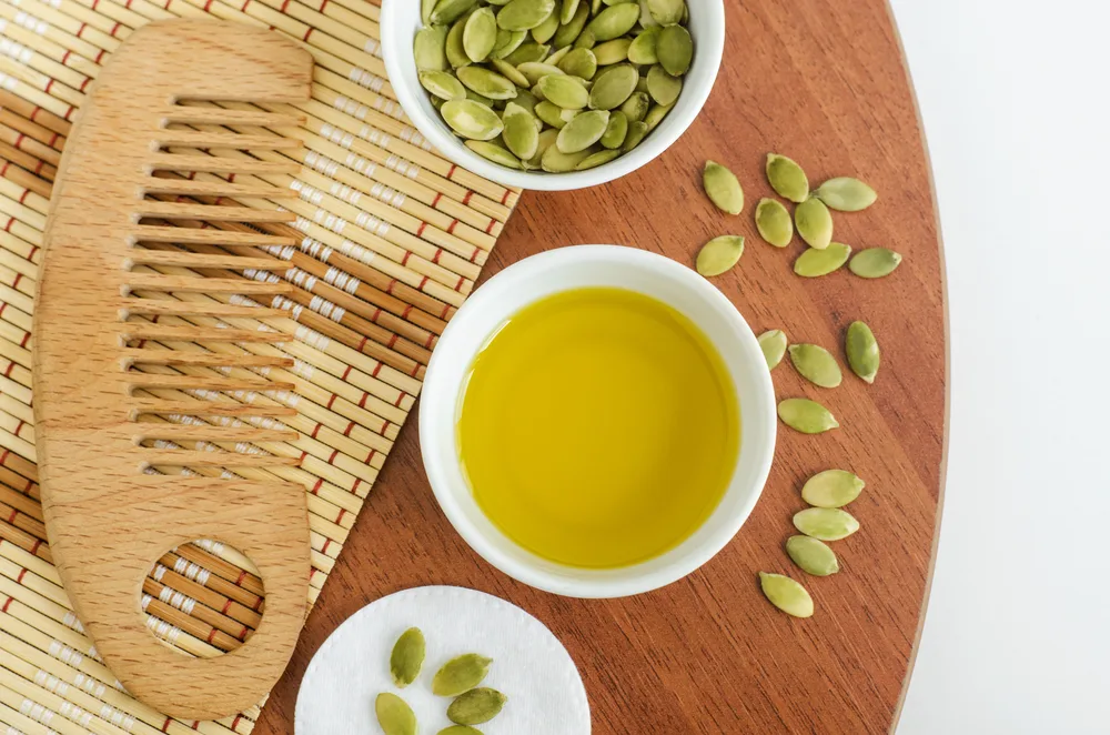 Image of pumpkin seed oil for hair on a wooden table