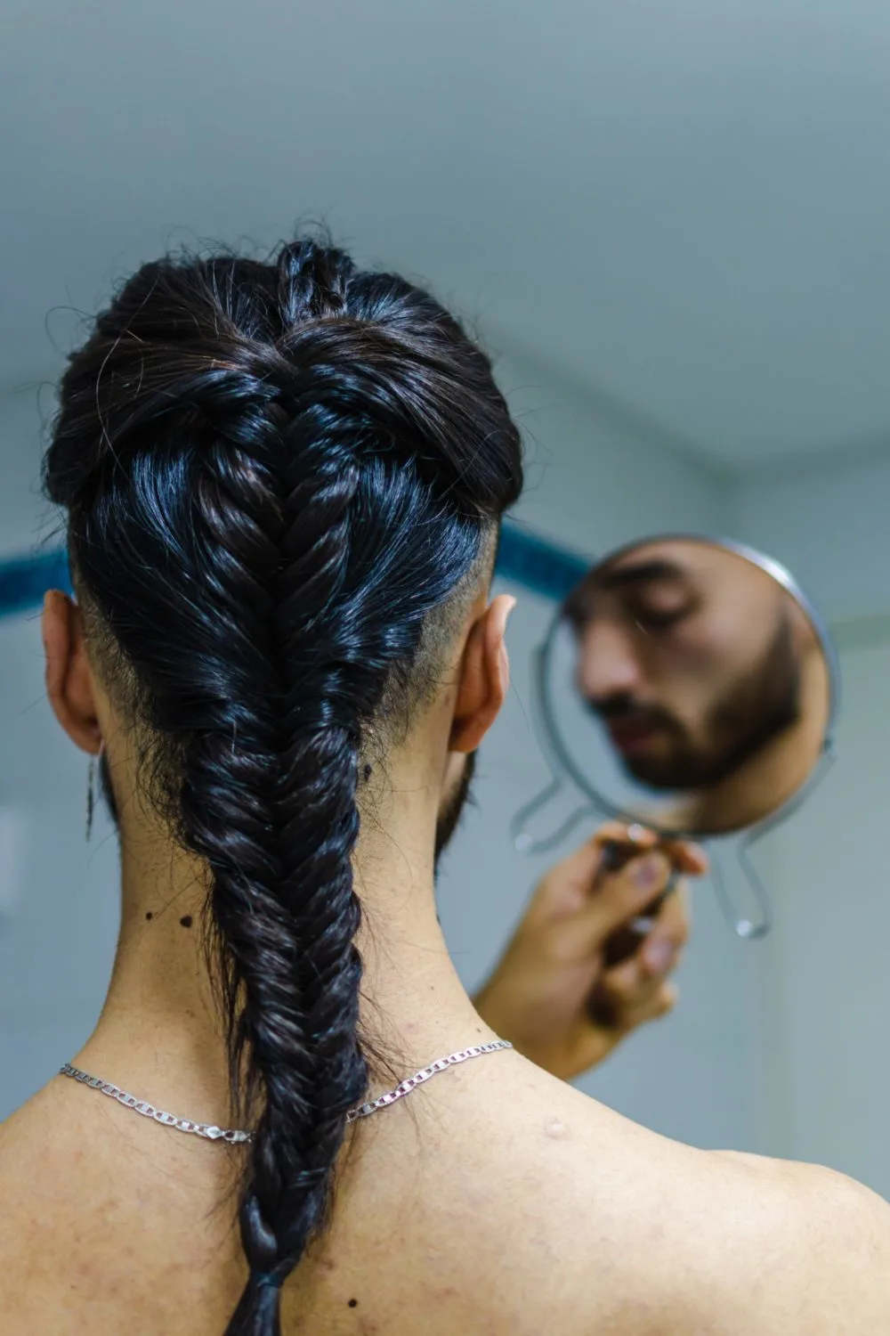 Twisted Fishtail White Mens Braid on a guy holding a mirror to his forehead