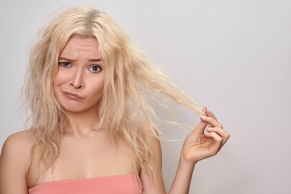 Gorgeous woman with damaged bleached hair holding her locks up