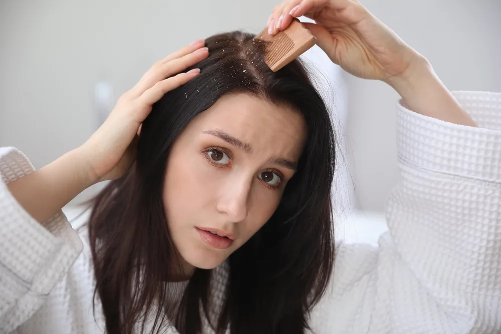 Woman treating her scalp with a wooden comb and wondering "should I condition my scalp"