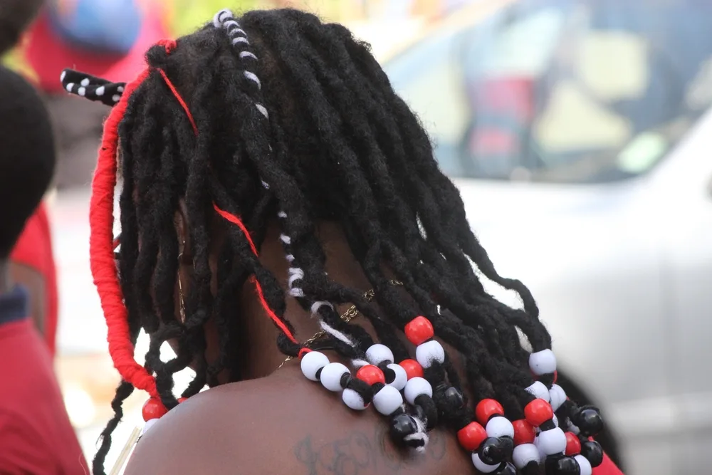Port of Spain, Trinidad - August 31, 2022: Rasta lady with beads in her hair representing the colors of the national flag on Trinidad and Tobago's 60th Independence Anniversary parade for a piece on braids with beads